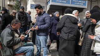 פלסטינים מחליפים כספים במסוף בנק ברמאללה