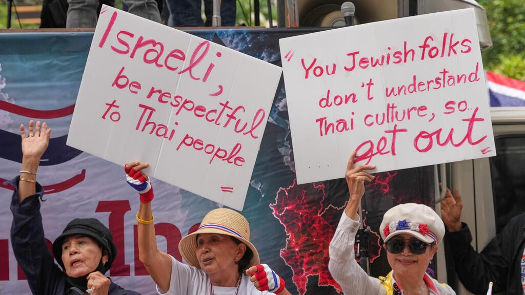 "אתם היהודים לא מבינים את התרבות התאילנדית, אז צאו החוצה"(AP Photo/Sakchai Lalit) (AP Photo/Sakchai Lalit) מפגינים נושאים שלטים במהלך מחאה מול שגרירות ישראל בבנגקוק
