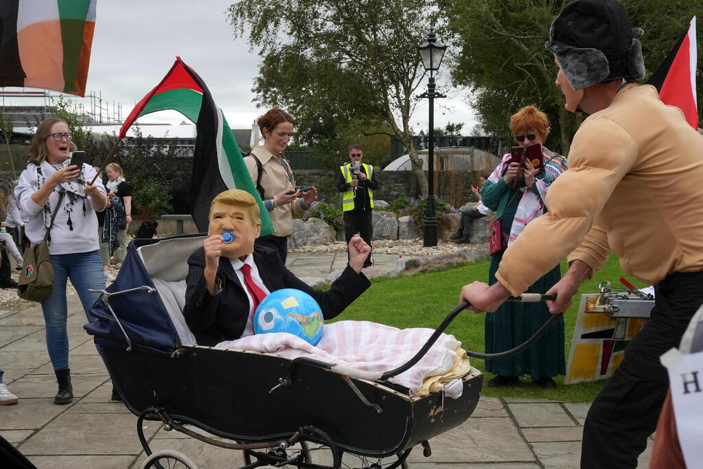 מובילים את "טראמפ" בעגלה עם כדור הארץ ודגלי פלסטין בהפגנות השנאה נגדו באירלנד (צילום: AP Photo/Kin Cheung) אירלנד הפגנות נגד ביקורו של נשיא ארה"ב דונלד טראמפ